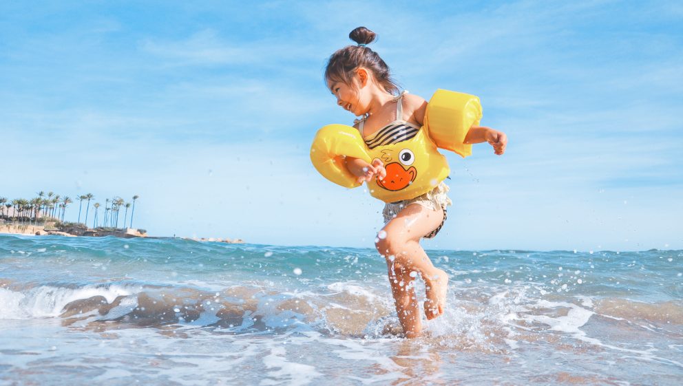 Photo of a child playing on a beach in the water