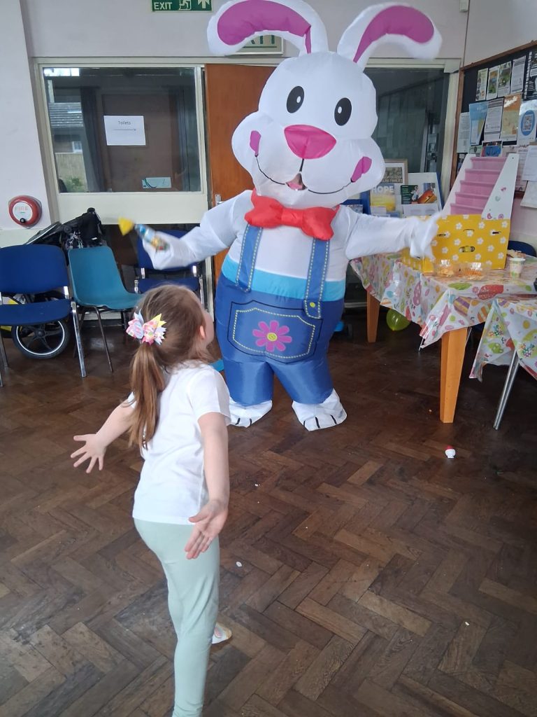 A little girl with her back to the camera runs to greet the Easter Bunny