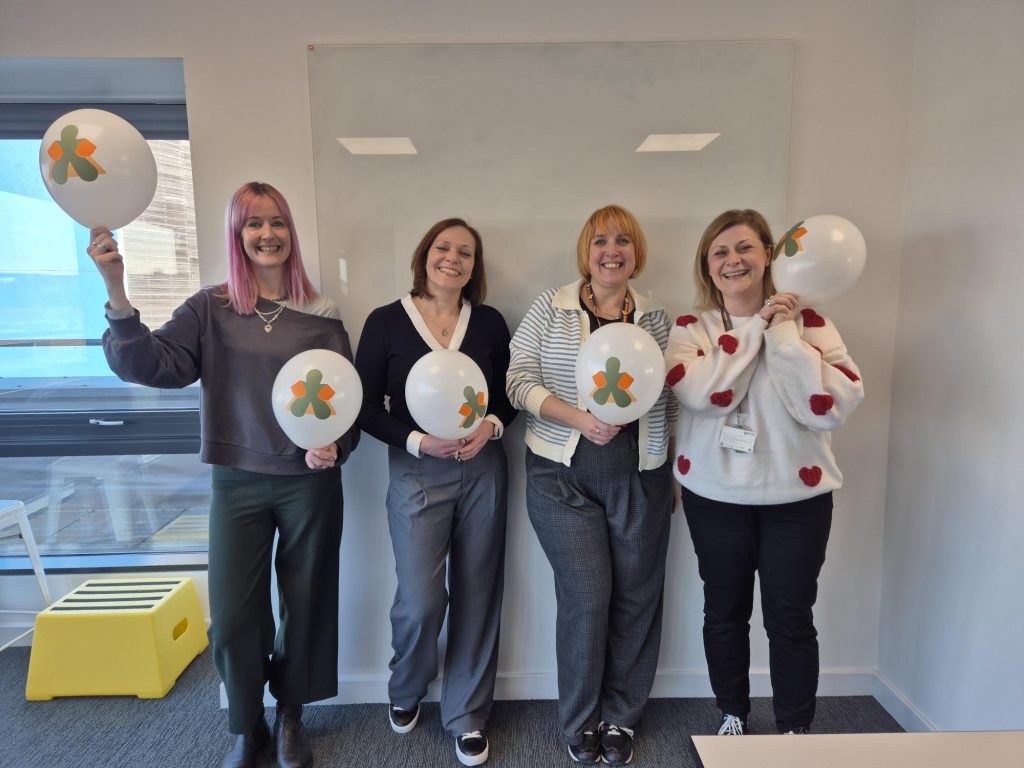 4 women celebrating, holding balloons with the Gingerbread logo